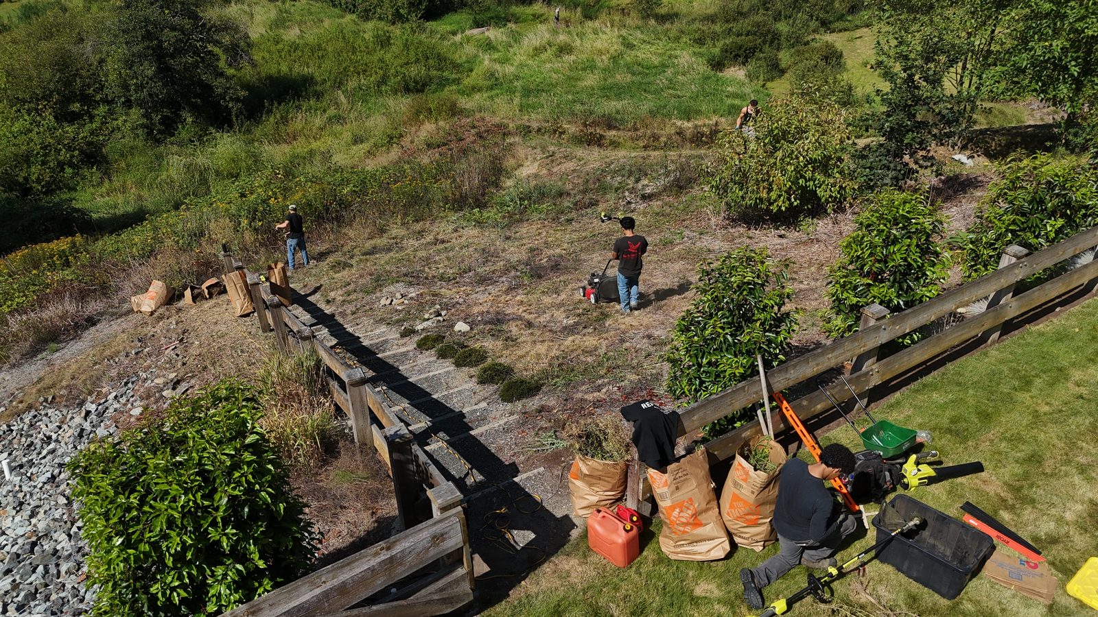 Aerial view of the crew clearing an overgrown slope — mowing, strimming and bagging green waste